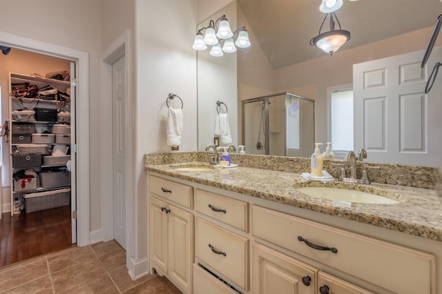  - full bathroom with a stall shower, double vanity, a walk in closet, and tile patterned floors