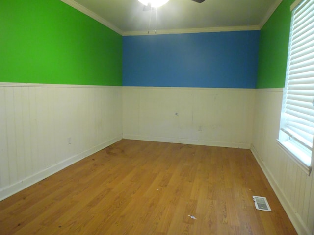  - spare room featuring wainscoting, ceiling fan, wood finished floors, and ornamental molding
