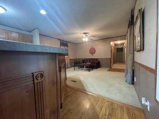 living room featuring ceiling fan, hardwood / wood-style floors, and a textured ceiling