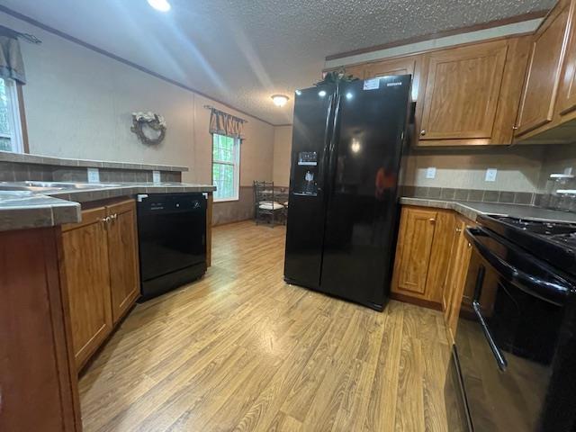 kitchen with light hardwood / wood-style floors, a textured ceiling, and black appliances