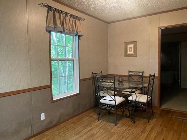 dining room featuring hardwood / wood-style flooring, a healthy amount of sunlight, and a textured ceiling