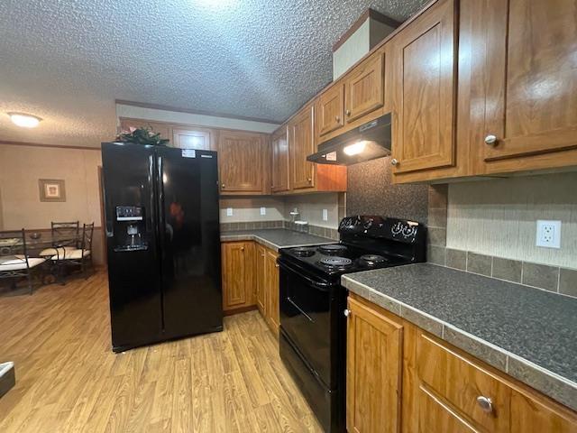 kitchen featuring tasteful backsplash, light hardwood / wood-style flooring, a textured ceiling, and black appliances