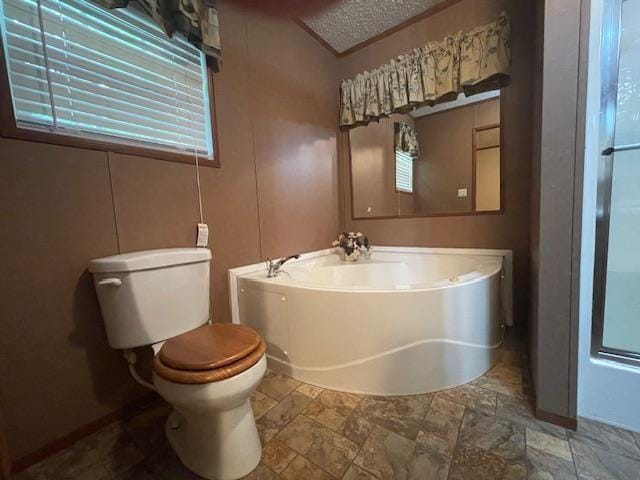 bathroom with a washtub, a textured ceiling, and toilet