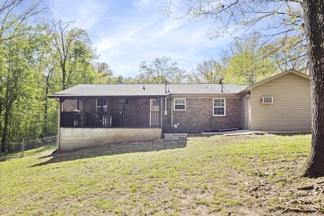 back of property featuring fence, a wall mounted air conditioner, brick siding, a lawn, and a sunroom