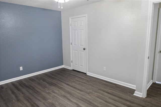 spare room featuring baseboards, dark wood-style floors, and ceiling fan