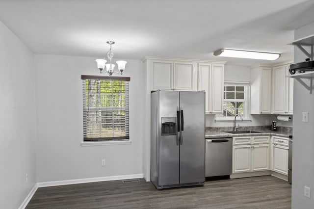 kitchen featuring stainless steel appliances, dark wood-style floors, a sink, baseboards, and an inviting chandelier