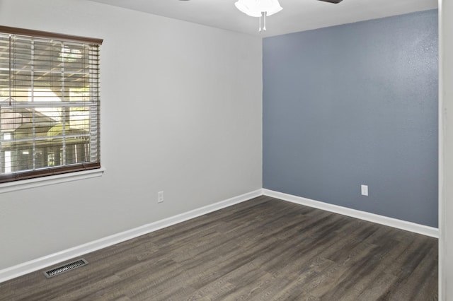 spare room with baseboards, visible vents, dark wood-style floors, and ceiling fan