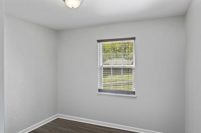 spare room featuring baseboards, a healthy amount of sunlight, and dark wood-style floors
