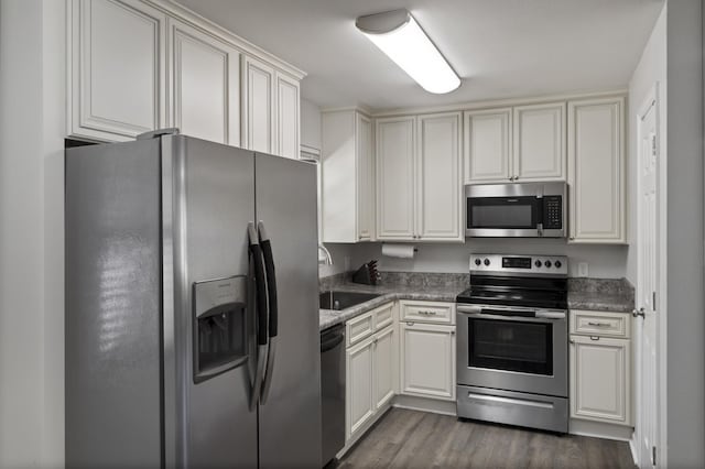 kitchen with dark wood-style flooring, stainless steel appliances, white cabinetry, and a sink