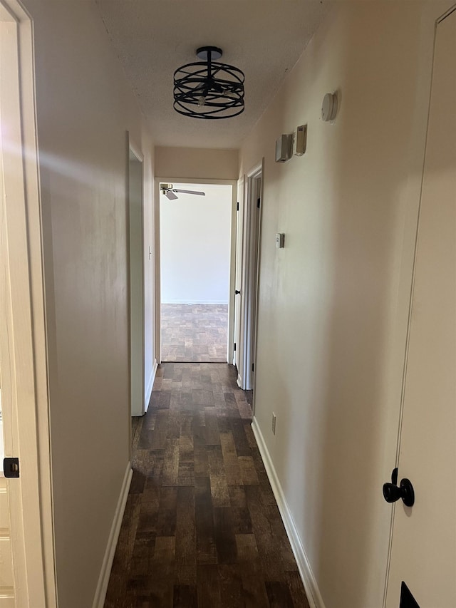 corridor with baseboards and dark wood-style flooring