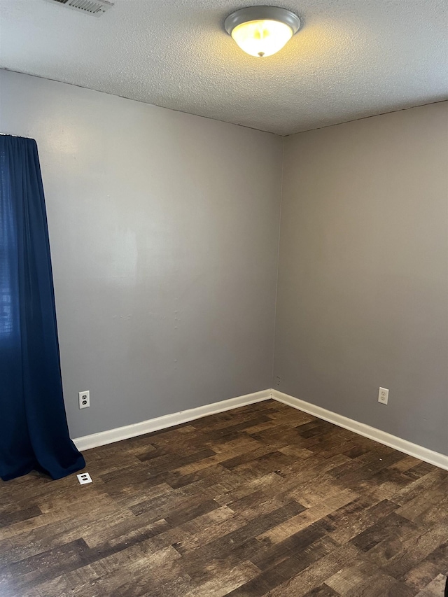 unfurnished room featuring dark wood-type flooring, baseboards, and a textured ceiling