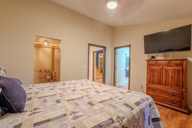 bedroom with vaulted ceiling, a closet, light wood-type flooring, and a ceiling fan