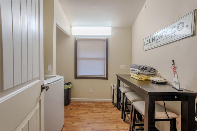 office area featuring visible vents, baseboards, light wood-style floors, a wall mounted AC, and washer / clothes dryer