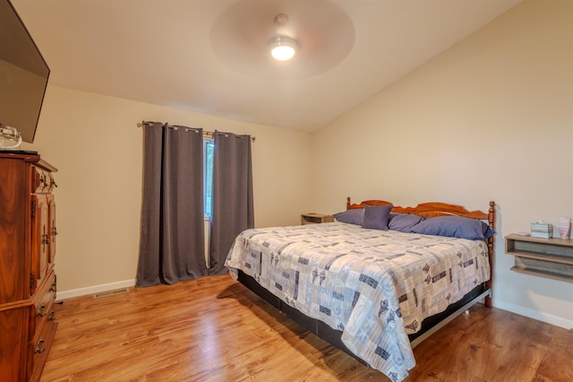 bedroom with lofted ceiling, light wood finished floors, and baseboards