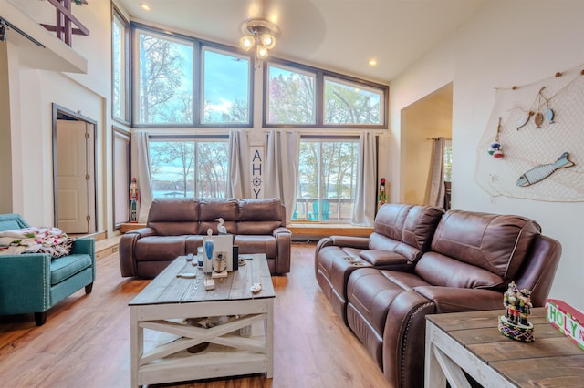 living room with light wood-style flooring, recessed lighting, and a towering ceiling