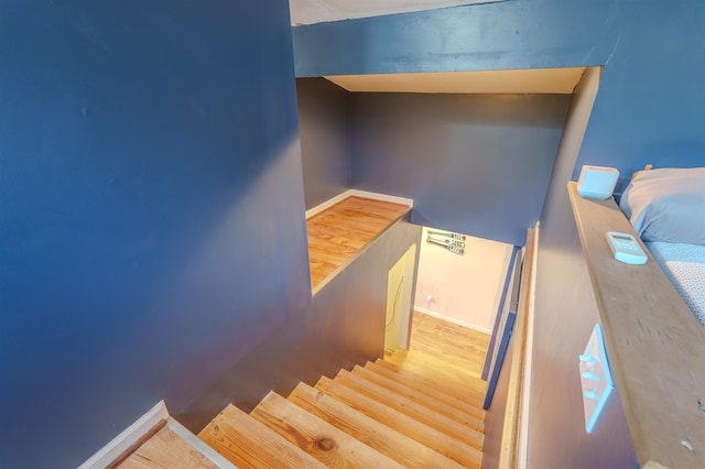 staircase featuring baseboards and wood finished floors