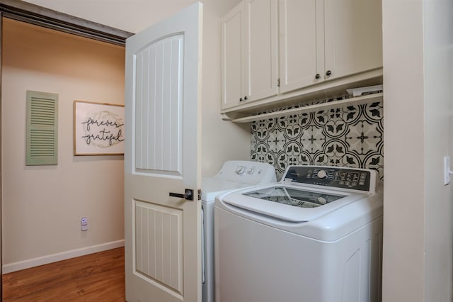 clothes washing area featuring cabinet space, baseboards, washer and dryer, and wood finished floors