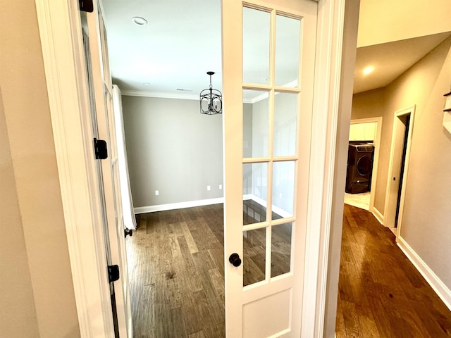 hallway with washer / clothes dryer, crown molding, and dark wood-type flooring