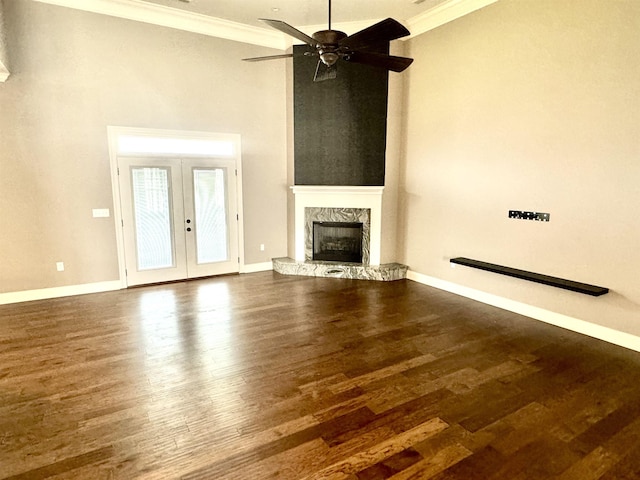 unfurnished living room with ceiling fan, french doors, a stone fireplace, dark hardwood / wood-style floors, and ornamental molding