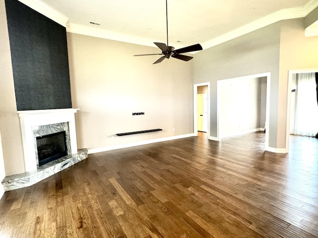 unfurnished living room featuring ceiling fan, ornamental molding, dark wood-type flooring, and a high end fireplace