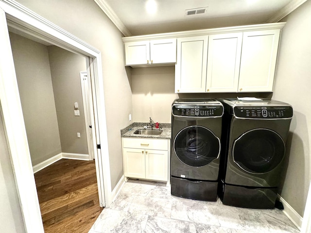 washroom featuring cabinets, separate washer and dryer, sink, and ornamental molding