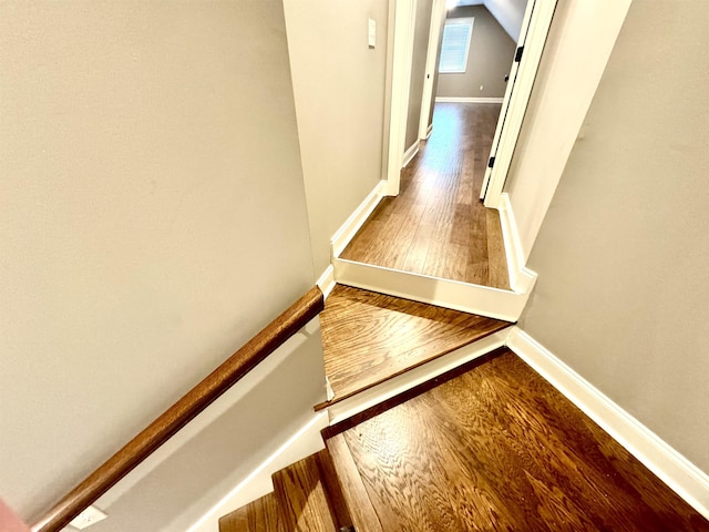 hallway with lofted ceiling and hardwood / wood-style flooring