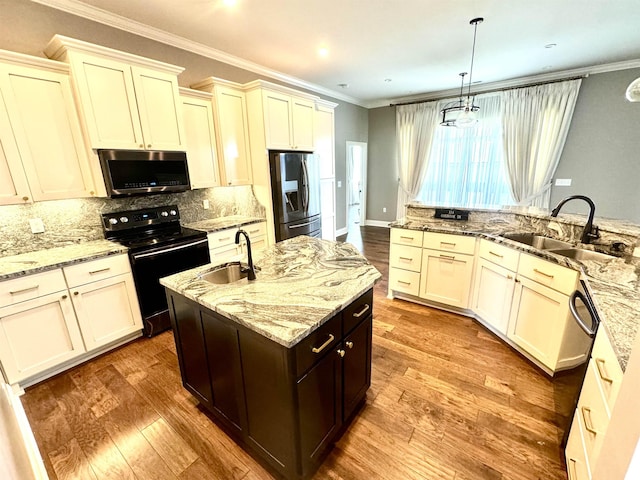 kitchen with light stone countertops, stainless steel appliances, a kitchen island with sink, sink, and hanging light fixtures