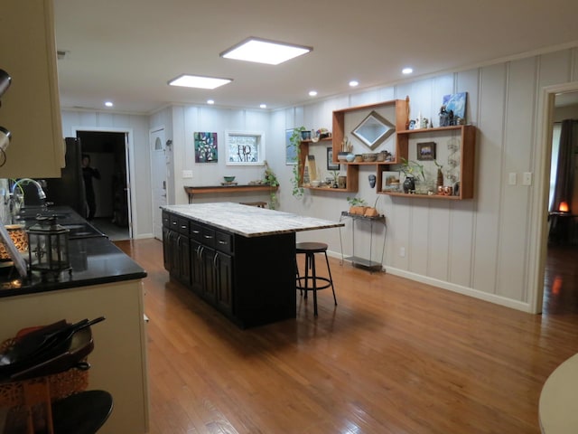 kitchen with a breakfast bar, a center island, light wood-type flooring, and sink