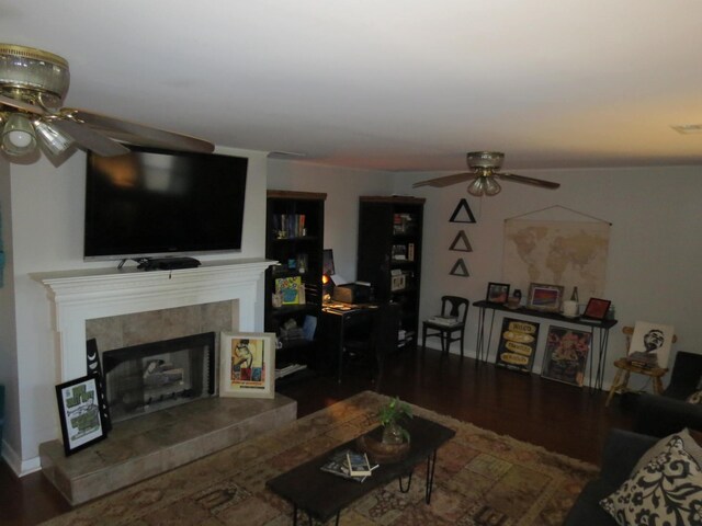 living room featuring hardwood / wood-style floors, ceiling fan, and a tiled fireplace