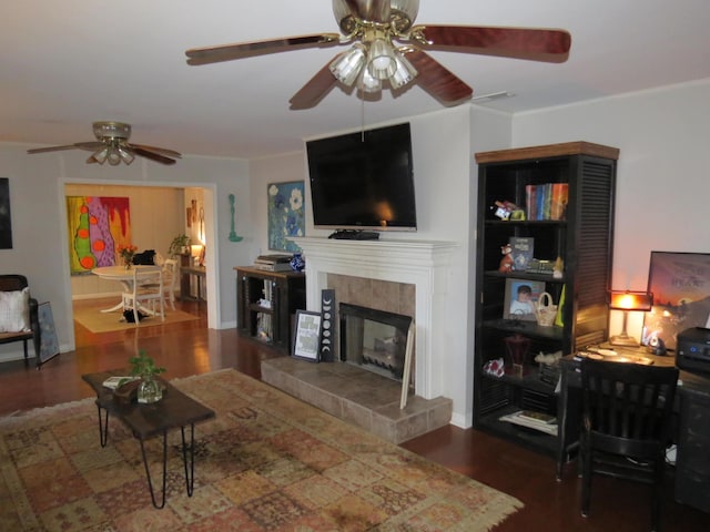 living room with crown molding, ceiling fan, dark hardwood / wood-style flooring, and a fireplace