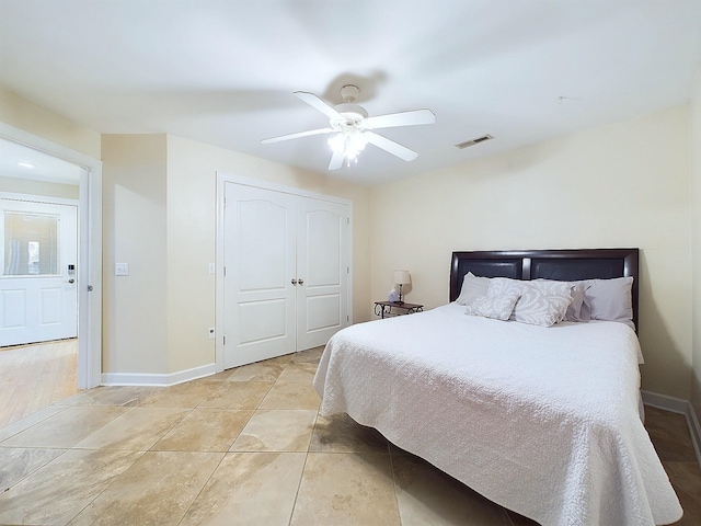 tiled bedroom with ceiling fan and a closet