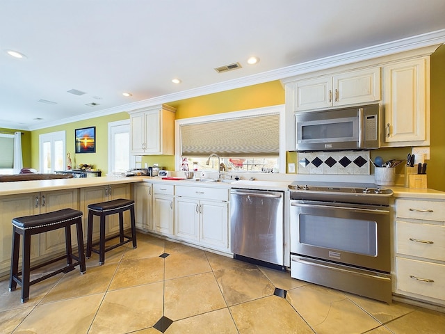 kitchen with appliances with stainless steel finishes, backsplash, ornamental molding, sink, and light tile patterned floors