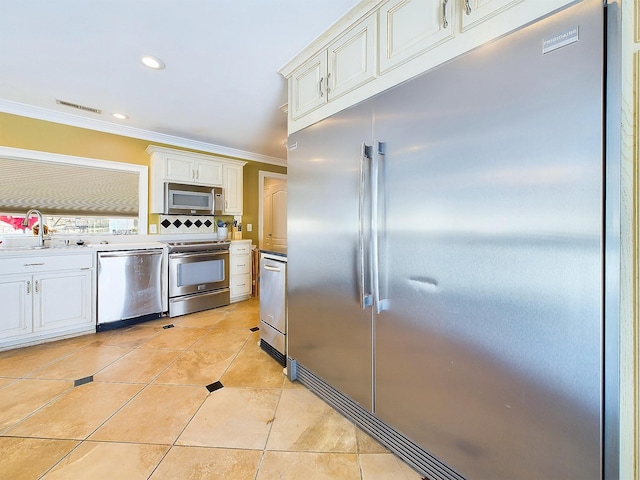 kitchen featuring decorative backsplash, sink, light tile patterned flooring, and appliances with stainless steel finishes