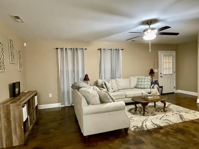 living area featuring baseboards, visible vents, and ceiling fan