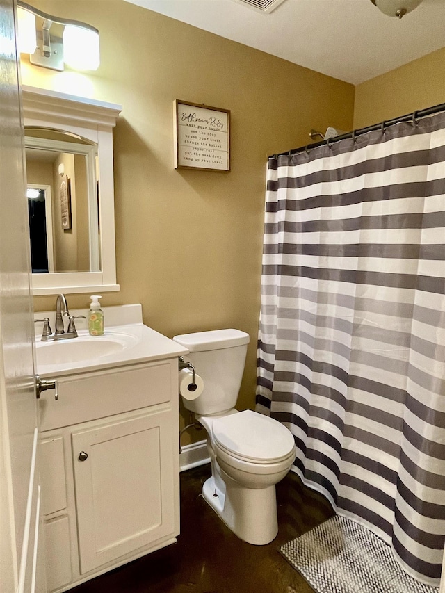 bathroom featuring toilet, a shower with shower curtain, and vanity