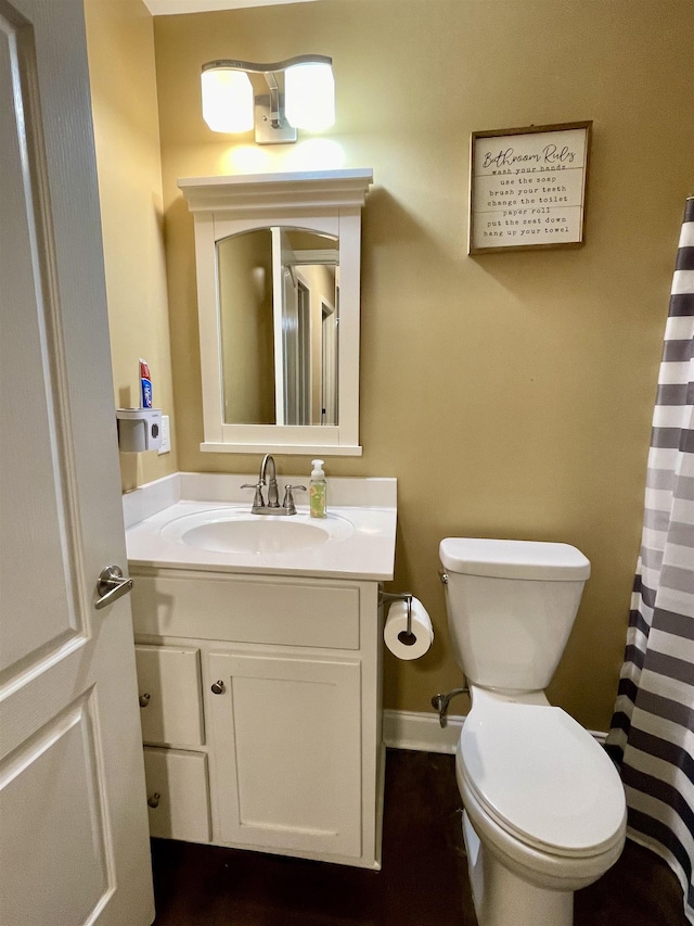 bathroom with toilet, a shower with curtain, baseboards, and vanity