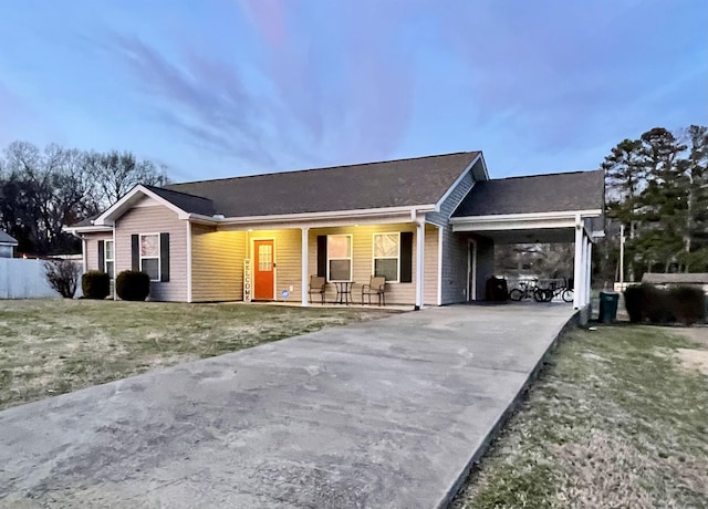 single story home featuring driveway, an attached carport, and a front yard