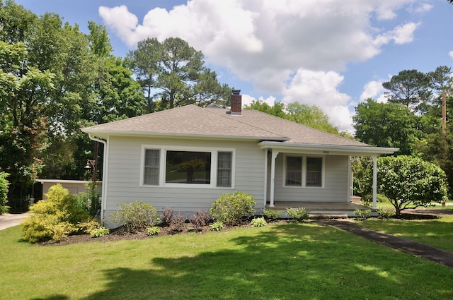  - view of front of property with a chimney, a front yard, covered porch, and roof with shingles