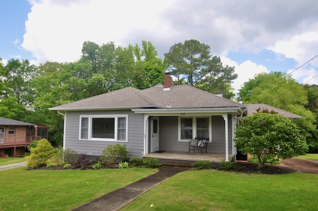  - bungalow-style home featuring covered porch, a chimney, a front lawn, and a shingled roof