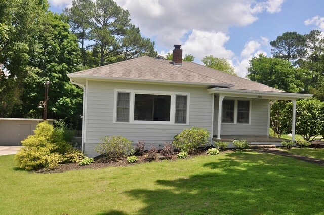  - rear view of property featuring a chimney, a lawn, roof with shingles, and covered porch