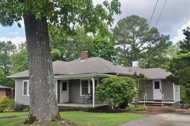  - view of front of property with a chimney, a shingled roof, and a front yard