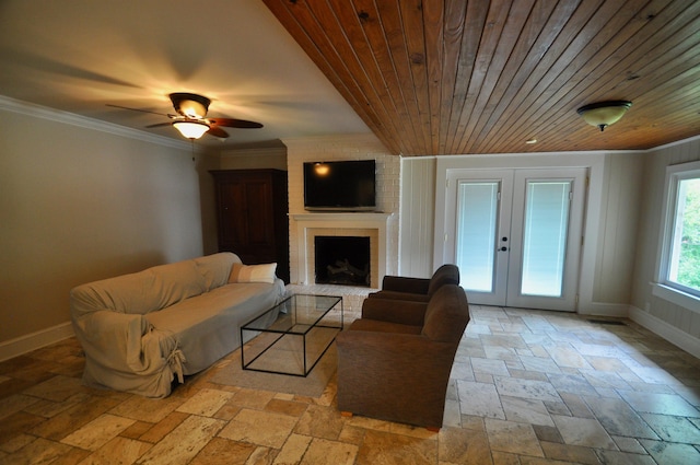  - living area featuring stone tile floors, baseboards, french doors, crown molding, and a brick fireplace