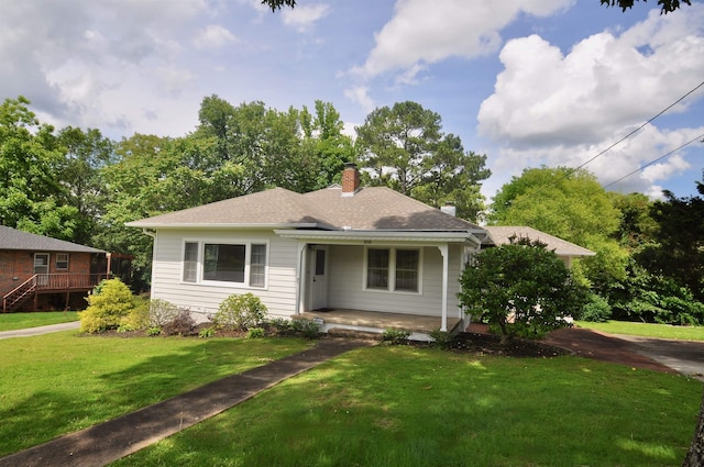  - view of front of house with covered porch, a chimney, a front yard, and a shingled roof