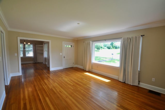  - empty room featuring crown molding, wood finished floors, plenty of natural light, and baseboards