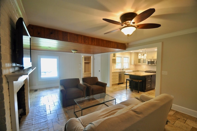  - living room featuring baseboards, a fireplace, a ceiling fan, ornamental molding, and stone tile floors