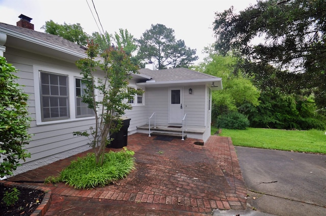  - rear view of property with a lawn, a chimney, and a shingled roof
