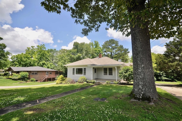  - view of front of home with a chimney, a front lawn, and a deck