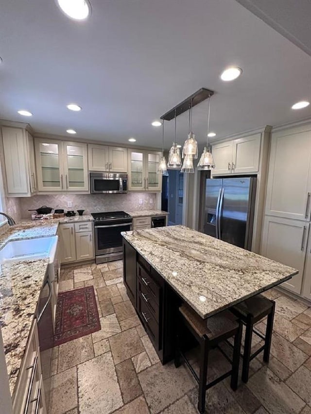  - kitchen with stainless steel appliances, stone tile floors, a sink, a center island, and recessed lighting