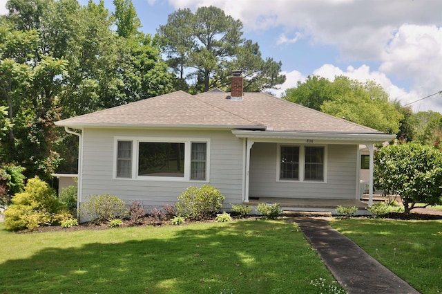  - bungalow-style home with a chimney, covered porch, a front yard, and roof with shingles