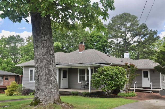  - view of front of property with a chimney, a shingled roof, and a front yard